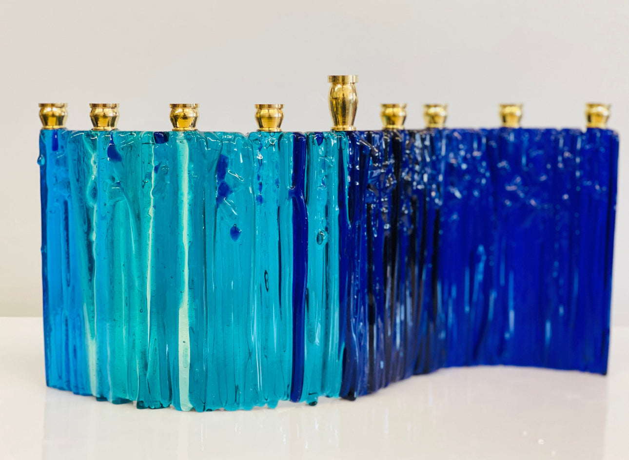 Cast glass menorah in turquoise and cobalt blue with brass candle cups