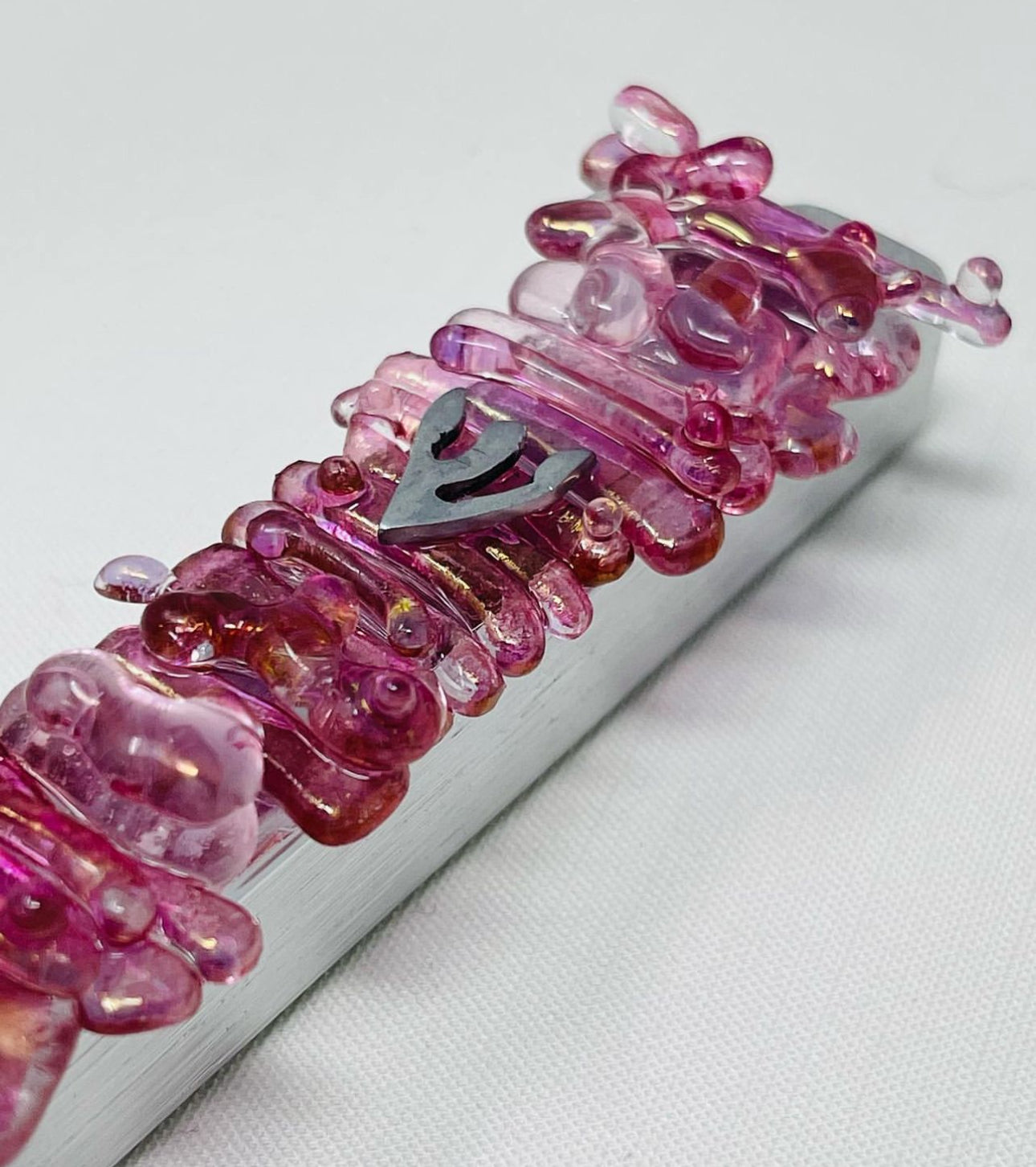 A wedding mezuzah in vibrant pink showcasing the transformation of the shards into a pearl-like jewel design.