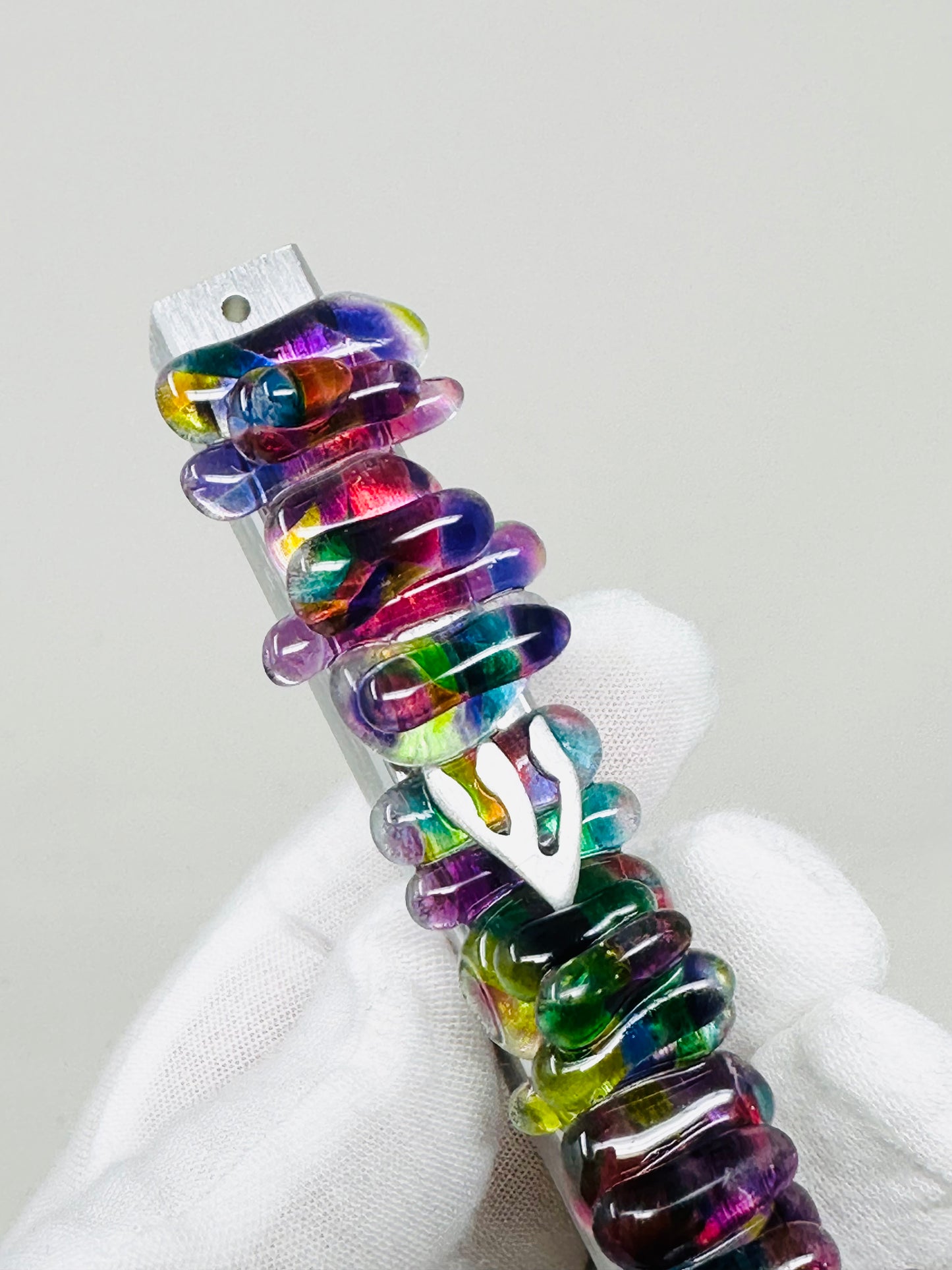 A close-up of a wedding mezuzah featuring a multicolored, pearl-like jewel in shades of purple, highlighting its unique design and craftsmanship.